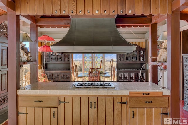 kitchen with island range hood, tile countertops, and stainless steel gas cooktop