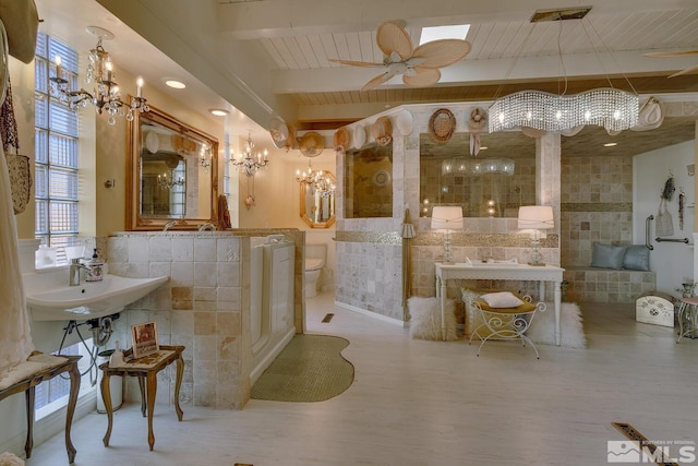 bathroom with toilet, sink, a chandelier, tile walls, and beamed ceiling