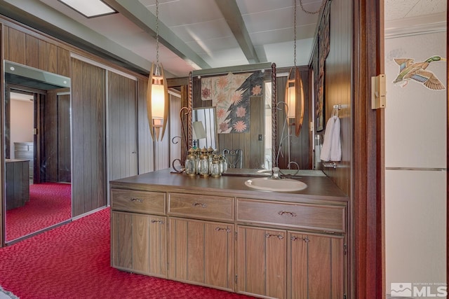 bathroom featuring beamed ceiling, vanity, and wooden walls