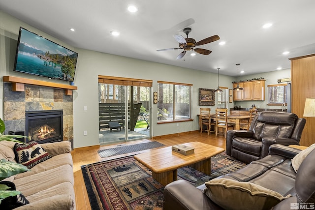 living room with a tile fireplace, ceiling fan, and light hardwood / wood-style floors