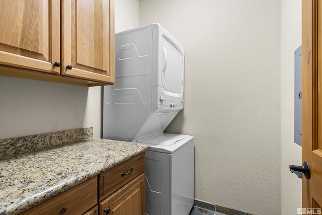 laundry room with cabinets and stacked washer / dryer