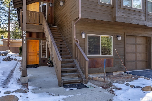 snow covered property entrance with a garage