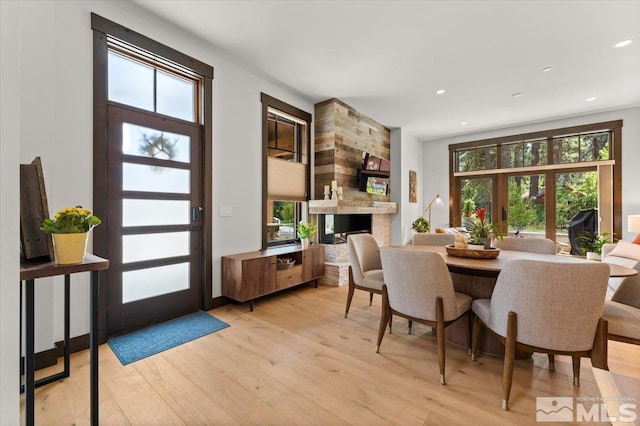 dining space with a multi sided fireplace and light hardwood / wood-style flooring