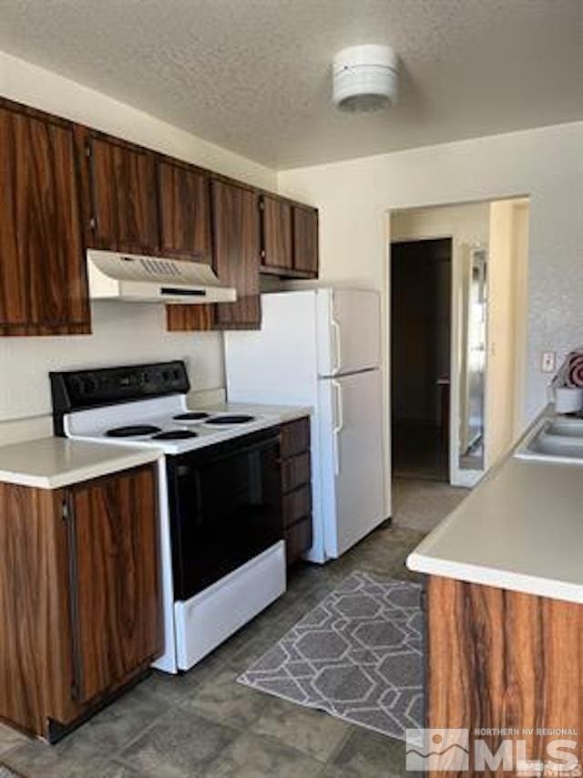 kitchen featuring dark brown cabinets, sink, a textured ceiling, and white appliances