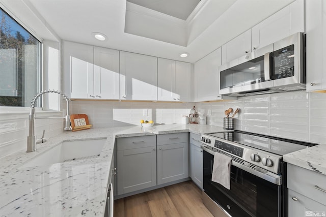 kitchen featuring stainless steel appliances, light stone countertops, sink, and white cabinets