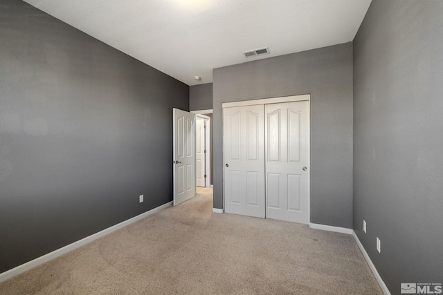 unfurnished bedroom with light colored carpet and a closet