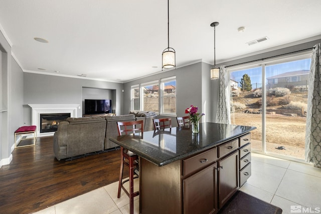 kitchen featuring pendant lighting, a wealth of natural light, a center island, and dark stone countertops