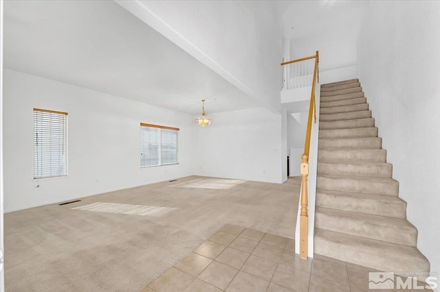 stairs with carpet, a healthy amount of sunlight, and a notable chandelier