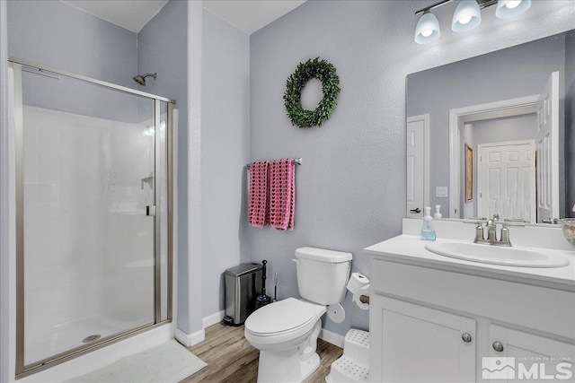 bathroom with hardwood / wood-style flooring, vanity, toilet, and a shower with shower door