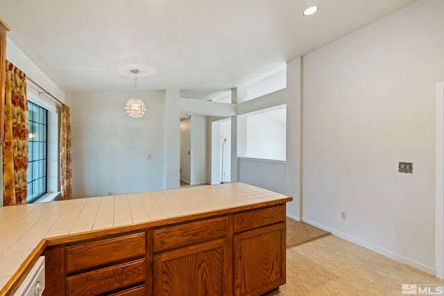 kitchen with hanging light fixtures, a notable chandelier, tile counters, and light colored carpet