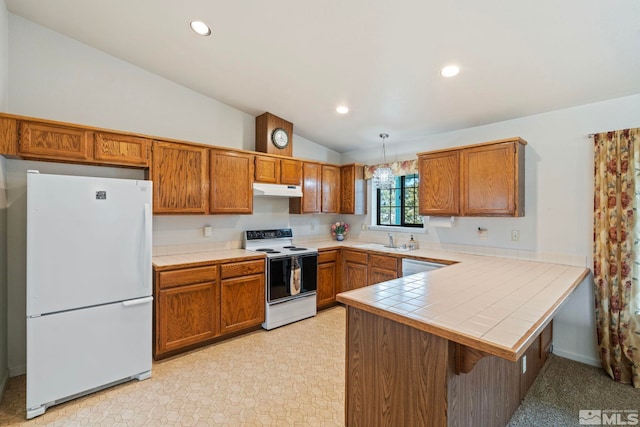 kitchen with tile countertops, pendant lighting, lofted ceiling, kitchen peninsula, and white appliances