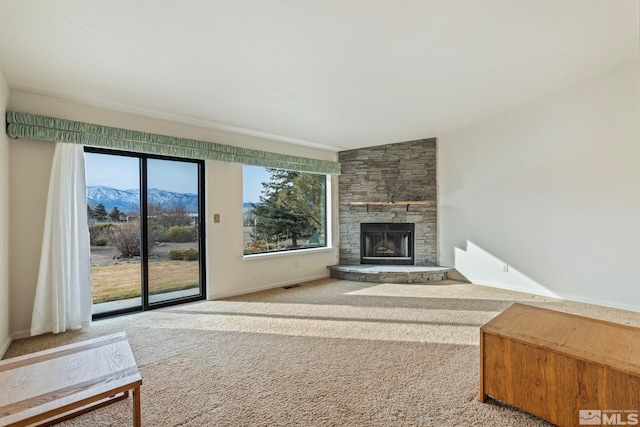 living room with a stone fireplace, a mountain view, and carpet floors