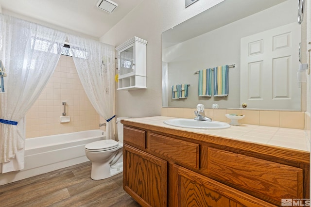 full bathroom featuring hardwood / wood-style flooring, vanity, shower / tub combo, and toilet