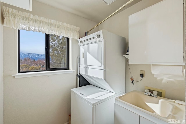 clothes washing area featuring stacked washer / dryer, a mountain view, and sink