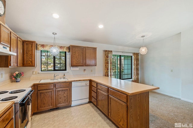 kitchen featuring sink, a chandelier, kitchen peninsula, pendant lighting, and white appliances