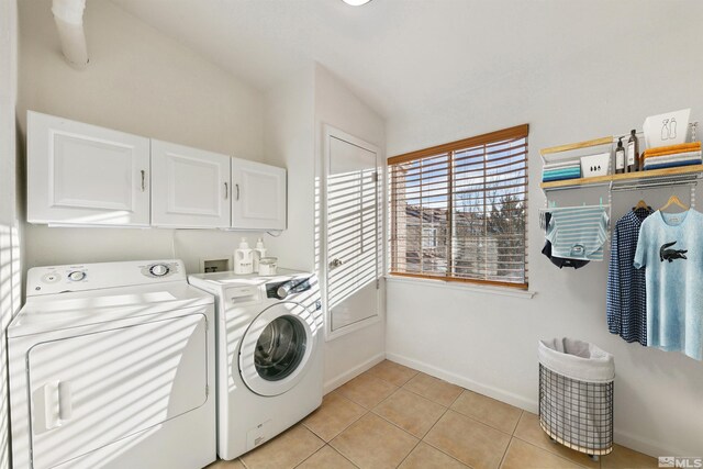 clothes washing area with separate washer and dryer, light tile patterned floors, and cabinets