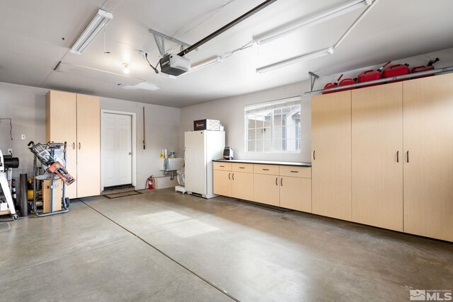 garage with sink, a garage door opener, and white refrigerator