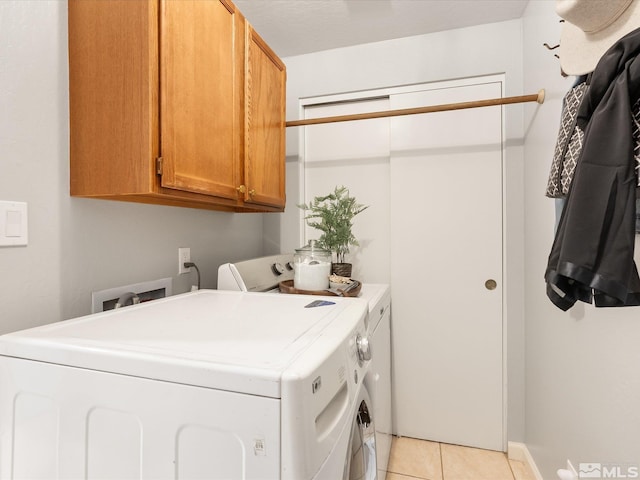 clothes washing area featuring cabinets, separate washer and dryer, and light tile patterned floors