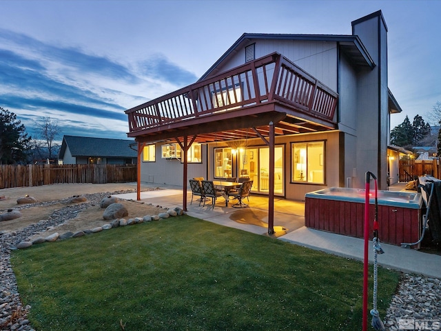 rear view of property featuring a wooden deck, a yard, a hot tub, and a patio area