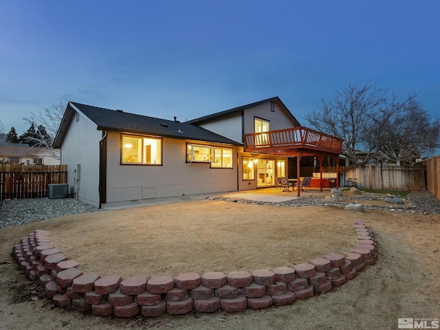 back house at dusk featuring central AC unit, a patio area, and a lawn