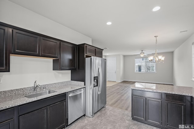 kitchen with appliances with stainless steel finishes, ceiling fan with notable chandelier, sink, hanging light fixtures, and dark brown cabinetry