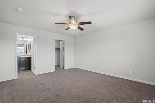 unfurnished bedroom with connected bathroom, a walk in closet, ceiling fan, light carpet, and a closet