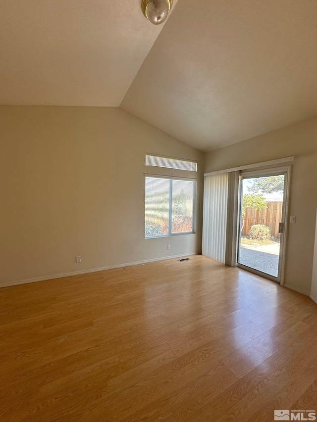 empty room featuring visible vents, vaulted ceiling, baseboards, and light wood-style floors
