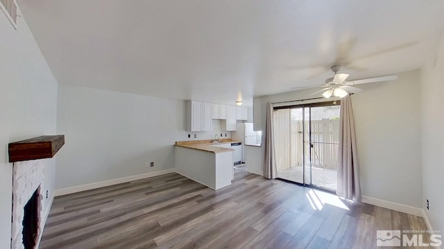 unfurnished living room with hardwood / wood-style flooring, sink, a fireplace, and ceiling fan