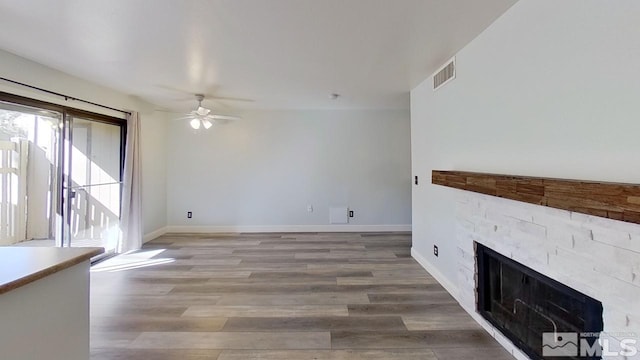 unfurnished living room featuring wood-type flooring, ceiling fan, and a fireplace