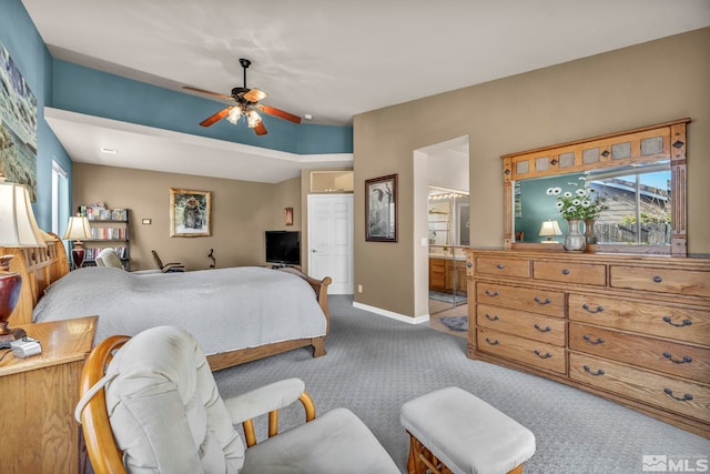 bedroom with ceiling fan, light colored carpet, and ensuite bath