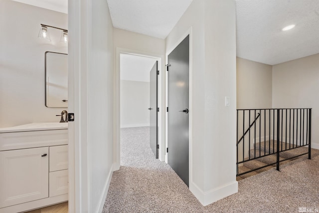 hall featuring light colored carpet and a textured ceiling