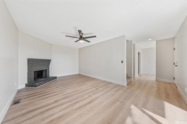 unfurnished living room with light hardwood / wood-style flooring, a textured ceiling, a fireplace, and ceiling fan