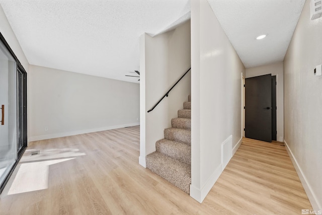 stairs with hardwood / wood-style floors and a textured ceiling