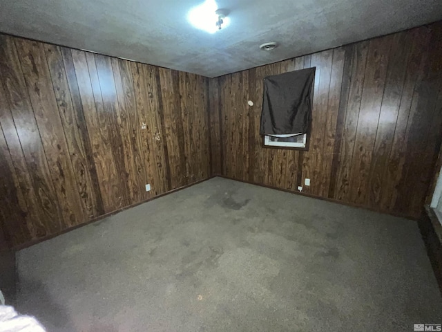 spare room featuring light carpet and wood walls