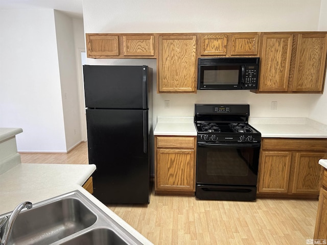 kitchen featuring sink, light hardwood / wood-style flooring, and black appliances