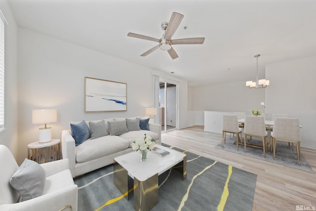 living room featuring ceiling fan with notable chandelier and light wood-type flooring