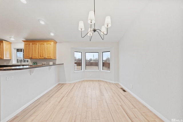 kitchen featuring a healthy amount of sunlight, sink, light hardwood / wood-style floors, and hanging light fixtures