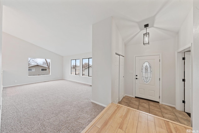 carpeted entrance foyer featuring vaulted ceiling