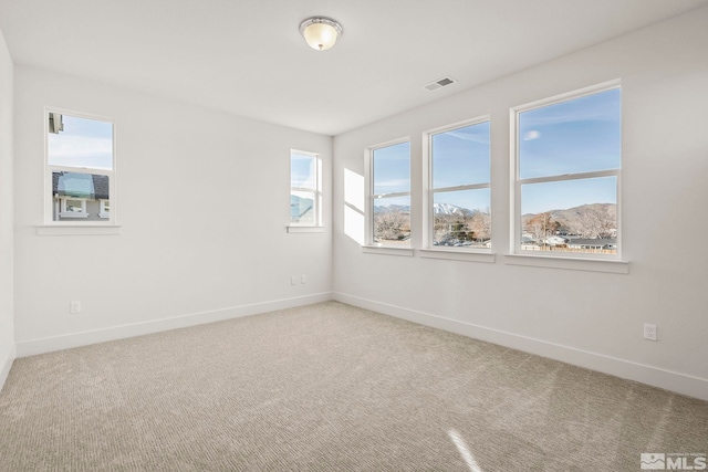 unfurnished room featuring a mountain view, carpet floors, and a healthy amount of sunlight