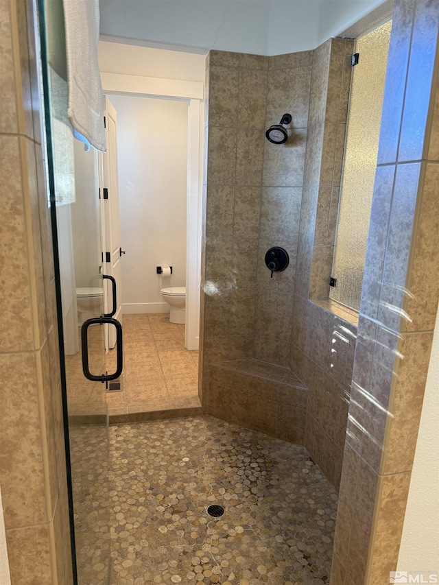 bathroom featuring tile patterned floors, toilet, and a shower with door