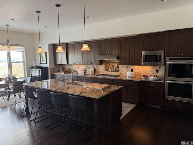 kitchen featuring appliances with stainless steel finishes, sink, a center island with sink, and pendant lighting