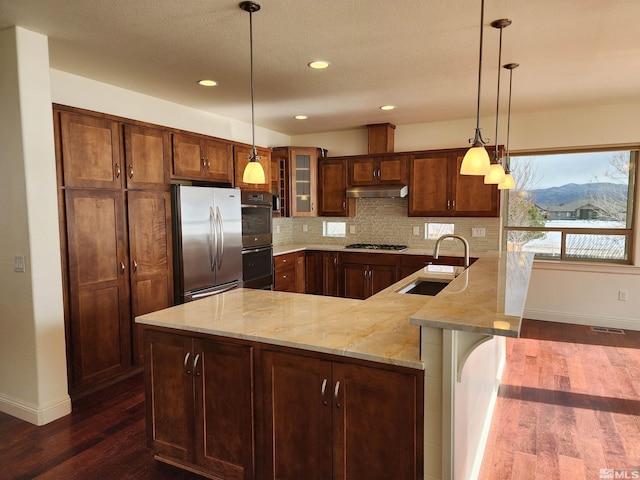 kitchen with a breakfast bar, sink, tasteful backsplash, kitchen peninsula, and stainless steel appliances