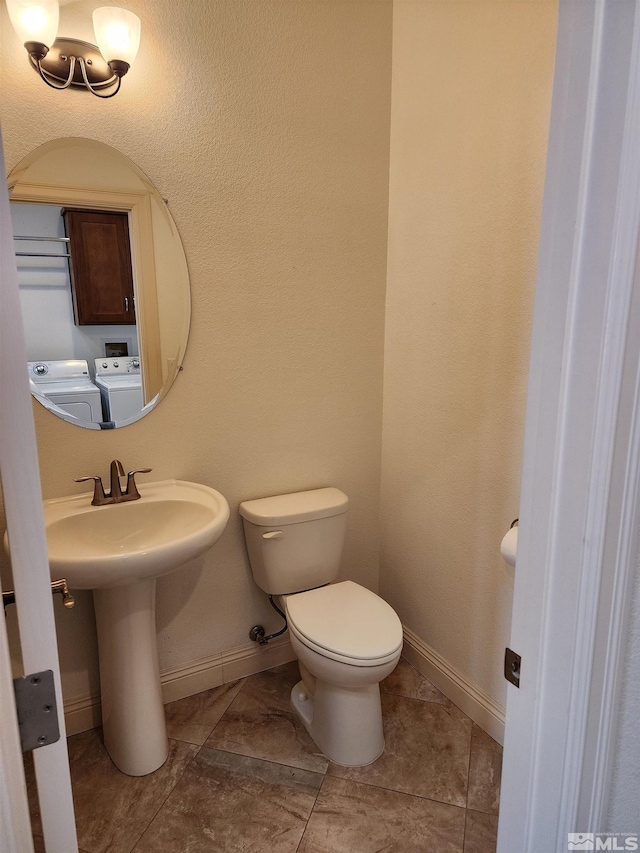 bathroom with separate washer and dryer, tile patterned flooring, and toilet