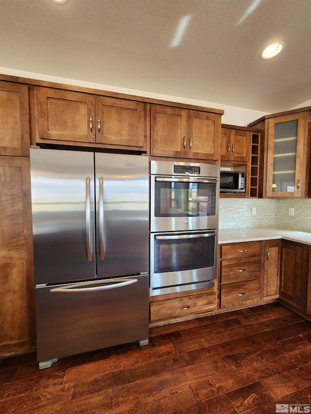 kitchen with stainless steel appliances, dark hardwood / wood-style flooring, a textured ceiling, and backsplash