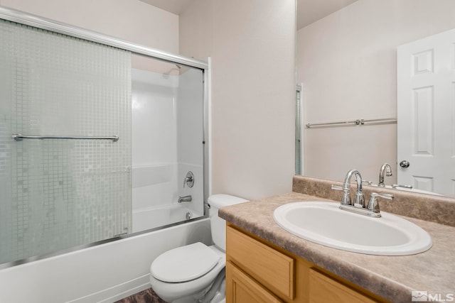 full bathroom with vanity, bath / shower combo with glass door, and toilet