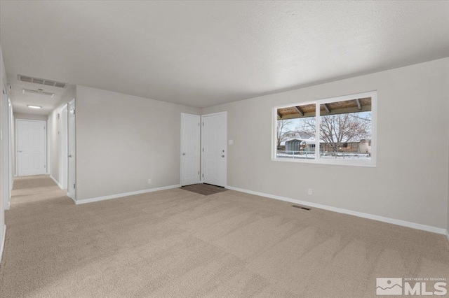 unfurnished room featuring light carpet and a textured ceiling