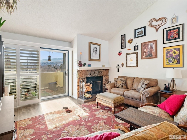 living room with lofted ceiling, a textured ceiling, a stone fireplace, and light hardwood / wood-style floors