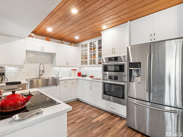 kitchen featuring sink, wooden ceiling, appliances with stainless steel finishes, white cabinets, and backsplash