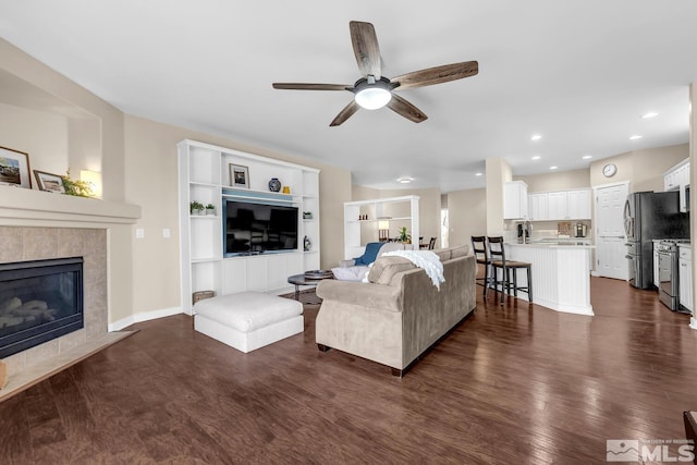 living room featuring a tile fireplace, ceiling fan, and dark hardwood / wood-style flooring