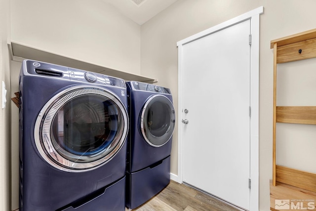 laundry room with independent washer and dryer and light hardwood / wood-style flooring